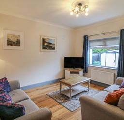 A living room with a television and seating at No 1 Lodge Wood, Kenmare, County Kerry