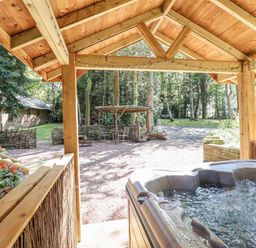 A hot tub with a view of a garden area featuring a table and chairs at Tanglewood Shepherds Hut Welshpool
