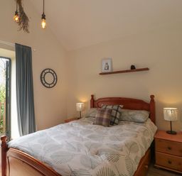A bedroom with a wooden bed and bedside tables with lamps at The Cart Shed in Barwick near Yeovil Somerset