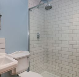 A bathroom with a sink toilet and a glass shower enclosure with white tile at The Cart Shed in Barwick near Yeovil Somerset