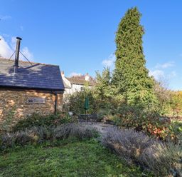 A garden with a shed, patio furniture, and trees at The Cart Shed in Barwick near Yeovil, Somerset