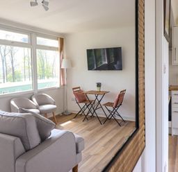 A living room with two armchairs a small table with two chairs and a wall-mounted TV at Hill View in Bryncrug near Tywyn