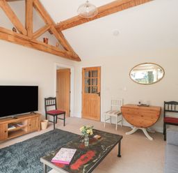 A living room with wooden beams a television on a stand chairs and a coffee table at Orchard View in Redmary D Abitot near Hartpury