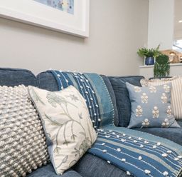 A blue sofa with four cushions and a blue patterned throw in a living room at Breeze Cottage in Falmouth