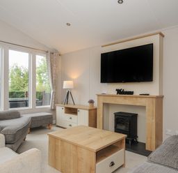 A living room with a sofa armchair coffee table fireplace and television at Lodge 59 at Riviera Bay Coastal Retreat in Brixham