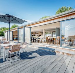 An outdoor dining area with tables and umbrellas at Lodge 62 at Riviera Bay Coastal Retreat in Brixham