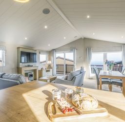 A living room with a sofa, television, and dining table at Lodge 73 at Riviera Bay Coastal Retreat, Brixham