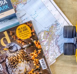 A magazine, map and binoculars on a table at Chalet 11 at Landscove Holiday Park Brixham