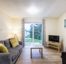A living room with a sofa and television at Chalet 34 at Landscove Holiday Park Brixham