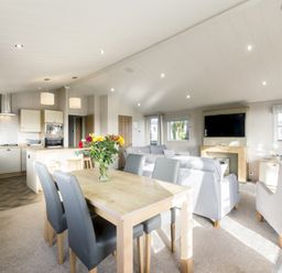 A living room with a dining table and kitchen area at Lodge 15 at Landscove Holiday Park Brixham
