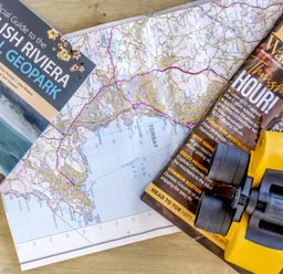 A map, a guide to the English Riviera, a bird watching magazine, and binoculars at Lodge 9 at Landscove Holiday Park, Brixham