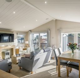 A living room with a sofa, table, and television at Lodge 11 at Landscove Holiday Park in Brixham