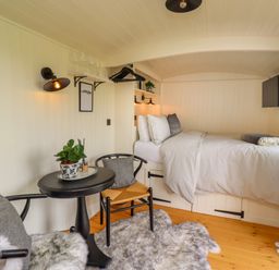 A small bedroom with a bed table chairs and a TV at La'al Ling in Penrith