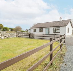 A single-story house with a lawn and brown wooden fence at Rossaveel Upper in Rossaveel County Galway