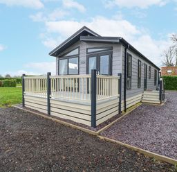 A modern prefabricated house with a small deck and stairs surrounded by grass and gravel paths at Wurzburc in Swaffham