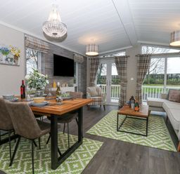 A combined dining and living room with a wooden dining table set with dishes and wine bottles and a seating area with a sofa and armchair at Wurzburc in Swaffham