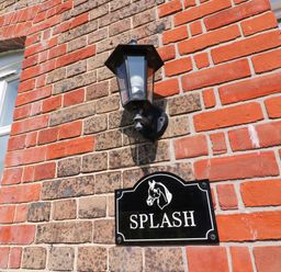 A black wall lantern and a house sign with a horse head and the word Splash on a brick wall at Splash in Weymouth