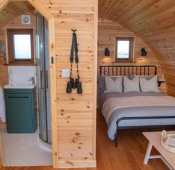 A wooden pod interior with a bed and bathroom at Glamping Pod 2 Presence in Lebberston
