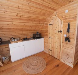 A small kitchenette with a kettle microwave sink and coffee setup inside a wooden cabin at Glamping Pod 2 Presence in Lebberston