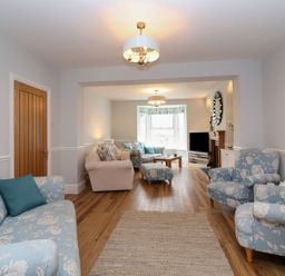 A living room with floral sofas and armchairs wooden floor and a TV at Metcalfe House in Compton Dundon