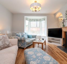 A living room with floral sofas a wooden coffee table a flat screen television and a fireplace at Metcalfe House in Compton Dundon