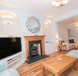 A living room with a fireplace a large TV a wooden coffee table and a beige corner sofa at Metcalfe House in Compton Dundon