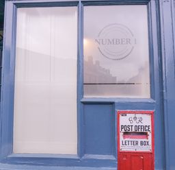 A blue door and window with a red post office letter box attached to the wall at Number 1 in Clare