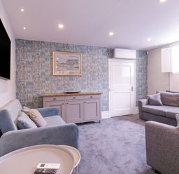 A living room with two sofas a sideboard a wall mounted TV and a window at Number 1 in Clare