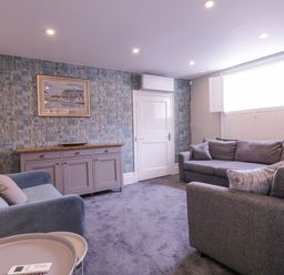 A living room with two sofas a sideboard a framed picture on a patterned wall and a window with shutters at Number 1 in Clare