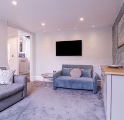 A living room with two sofas a wall-mounted TV a side table a cabinet and a framed picture at Number 1 in Clare