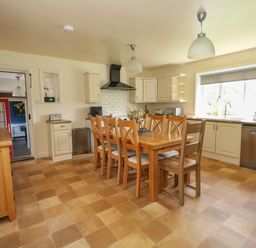 A kitchen with wooden dining table and chairs and cream cabinets at Rempstone Farmhouse in Corfe Castle
