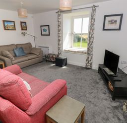 A living room with two sofas a window and a television at Grassholm View in Solva