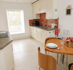 A kitchen with a window a dining table with plates glasses and a wine bucket at Grassholm View in Solva