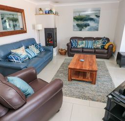 A living room with two sofas an armchair a wooden coffee table a rug a fireplace and a television at Llain Gwynfor in St Davids