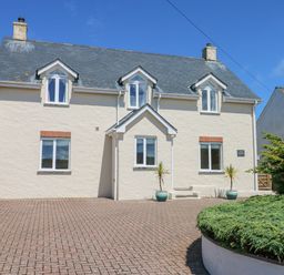 A two story house with three dormer windows and a paved driveway at Llain Gwynfor in St Davids