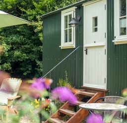 A green shed with steps and seating area at Collen in Aberaeron