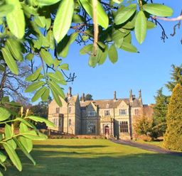 A large stone house with a driveway and lawn surrounded by trees and greenery at The Hall in Belford