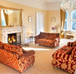 A living room with patterned sofas a fireplace and large windows at The Hall in Belford