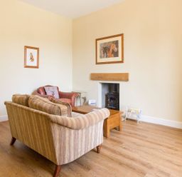 A sitting room with a sofa armchair wooden coffee table and framed pictures on the wall at The Coach House in Belford