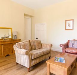 A living room with a striped sofa a leather armchair and wooden furniture at The Coach House in Belford