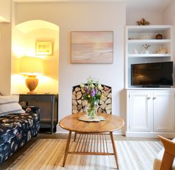 A living room with a floral sofa a wooden coffee table and a television at Compass Cottage in Aldeburgh