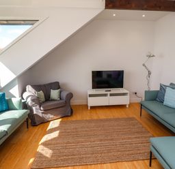 A living room with sofas armchair television and a rug at Ocean View in Alnmouth