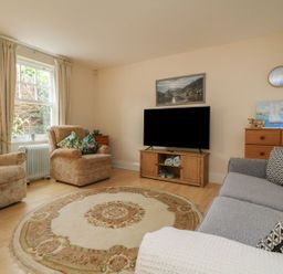 A living room with armchairs a sofa a round rug a television and a wooden cabinet at Archie's in Minehead