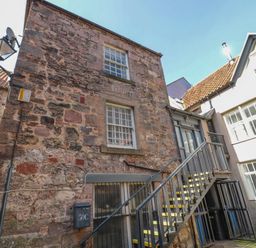 An exterior view of a stone building with metal stairs leading to a second-floor door at The Old Factory House in Berwick-Upon-Tweed