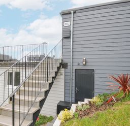 Exterior view of a building with stairs leading to a rooftop terrace and a garden with plants at 100 Hillside Villas in Looe