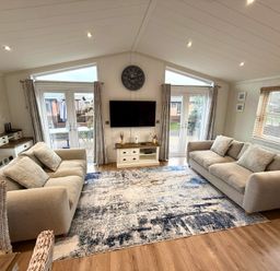 A living room with a television and large windows at Lodge 18 - The Pines Runswick Bay