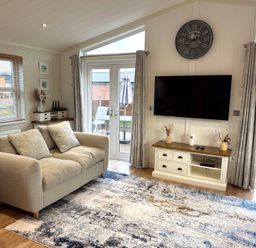 A living room with a sofa and television at Lodge 18 - The Pines Runswick Bay
