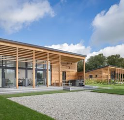 Two modern wooden houses with large glass windows and gravel area in front at Silver Birch in Dolton