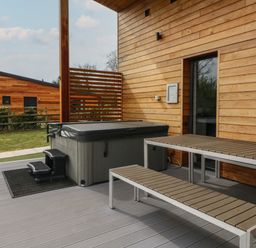An outdoor deck with a hot tub and a picnic table next to a wooden building at Cherry in Dolton