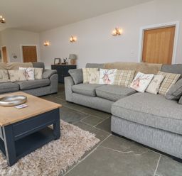 A living room with two gray sofas with patterned cushions and a blue coffee table on a rug at Cherry in Dolton